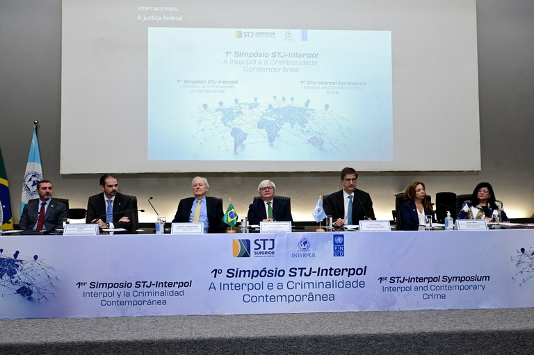Foto da mesa de abertura do evento com todas as autoridades sentadas e um painel no fundo