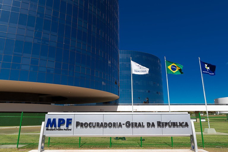 Foto dos prédios da Procuradoria-Geral da República. Na frente, a placa com o indicativo da instituição MPF e, entre a placa e o prédio, as bandeiras do Brasil, do Ministério Público e do Mercosul