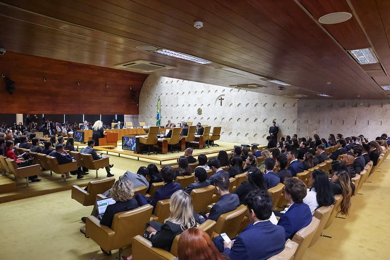 A foto mostra uma visão ampla do Plenário do Supremo Tribunal Federal (STF), em Brasília, durante uma sessão deliberativa. A foto traz uma vista em ângulo inclinado do salão principal, destacando a plateia em primeiro plano e a mesa do tribunal ao fundo.