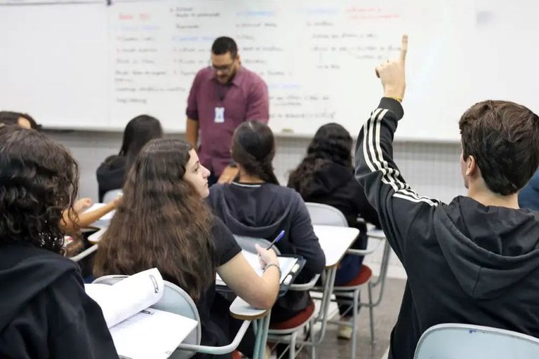 Foto de sala de aula com professor e alunos.
