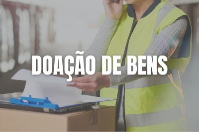 Imagem em plano fechado de trabalhadora da logística em armazém olhando papéis em uma prancheta sobre caixas.