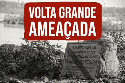 Foto em preto e branco de uma placa onde está escrito Terra Protegida. A placa está no chão. Em vermelho se lê Volta Grande Ameaçada