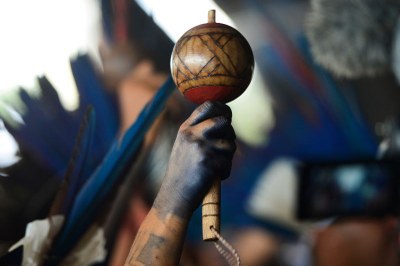 Foto da mão de um indígena segurando um maracá.