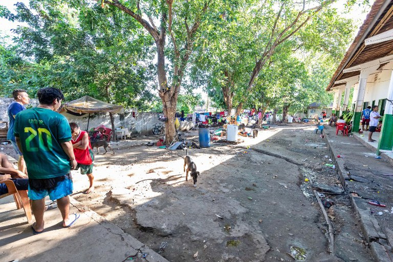 Foto mostra o quintal de assentamento da comunidade warao. O chão é de terra batida e há roupas no varão