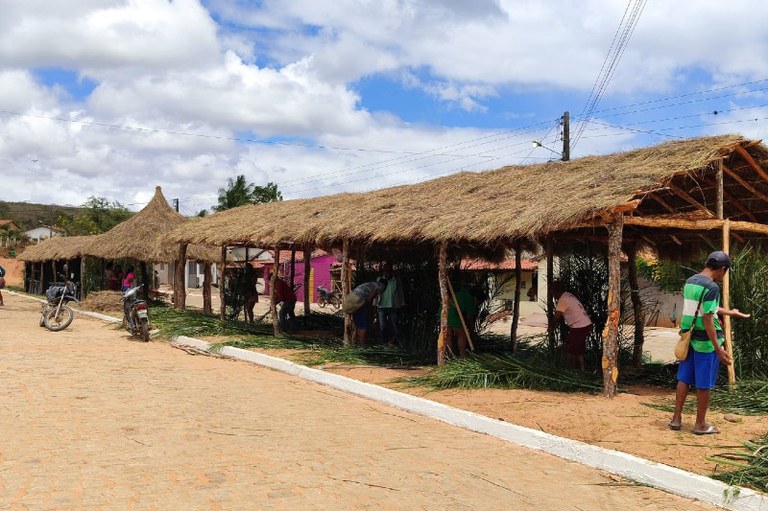 Foto mostra indígenas construindo estruturas com folhas de palmeira