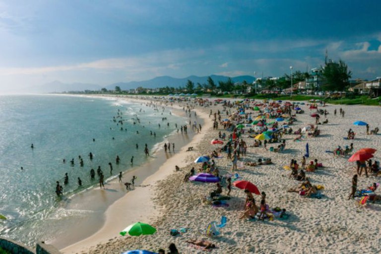 Foto área mostra a orla de uma praia em Saquarema mostrando o mar, a faixa de areia e barracas de praia