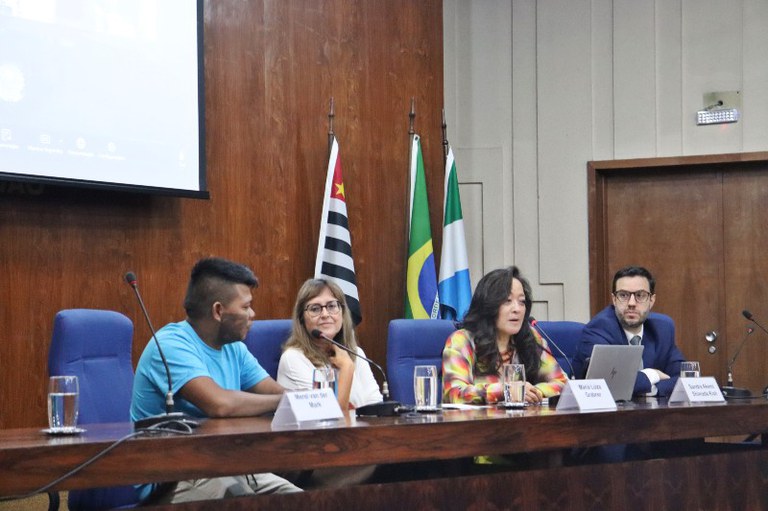Foto mostra mesa de abertura do evento com quatro pessoas