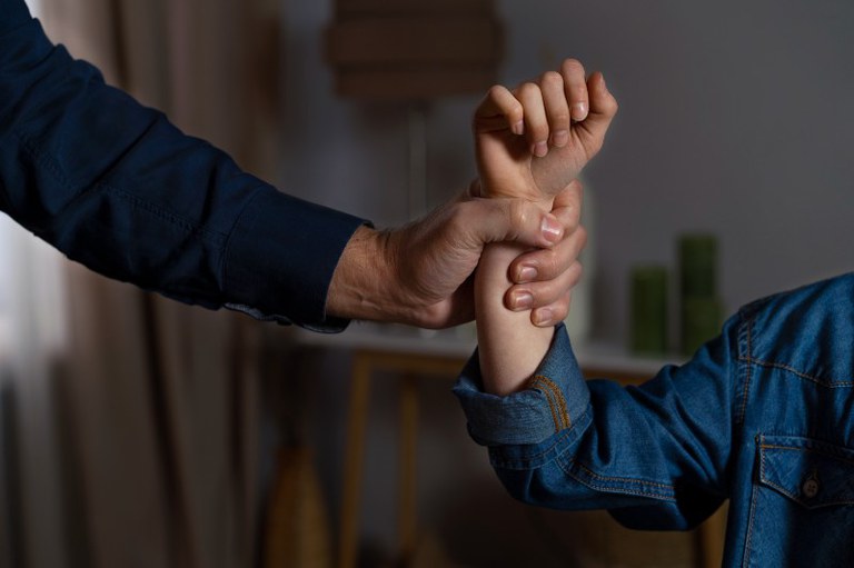 Foto mostra homem segurando à força braço de uma mulher