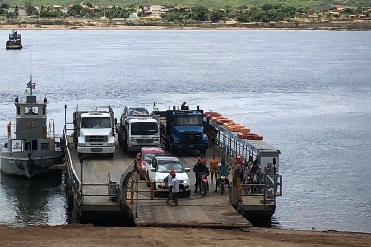 Fotografia de uma balsa sendo carregada com veículos, às margens do rio São Francisco, para travessia entre os municípios de Porto das Folhas (SE) e Pão de Açúcar (AL).
