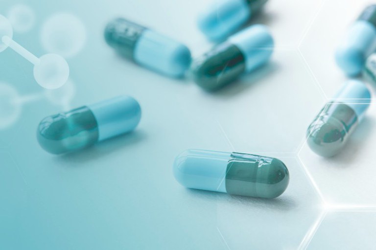 Imagem com fundo azul mostra pílulas da mesma cor