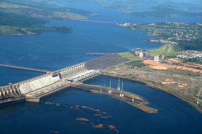 Vista aérea da represa de Tucuruí, com paredão de concreto e turbinas de água. A cidade está ao fundo da imagem. 