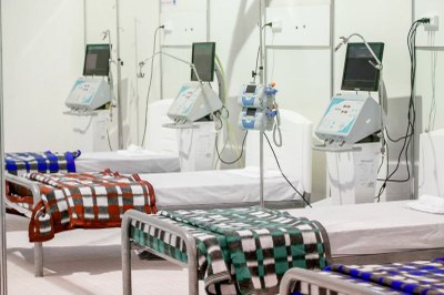 Camas de hospital, com respiradores ao lado de cada cama, entrecobertas por cobertores quadriculados e coloridos. 