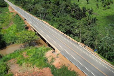 Foto aérea de uma estrada pavimentada, longa e reta, cercada por vegetação amazônica.