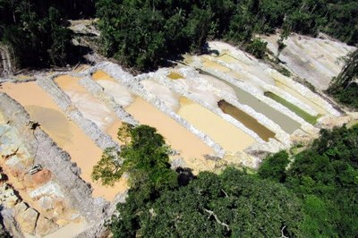Vista aérea de área de floresta e rio com desmatamento, erosão do solo e assoreamento de corpos d'água.