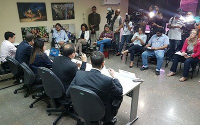 Representantes do Ministério Público do Estado do Pará, do Ministério Público Federal e da Defensoria Pública do Estado do Pará sentados em uma mesa em frente a repórteres em uma sala.