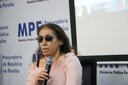 Gilvanedja Mendes, bibliotecária-documentalista da Universidade Federal da Paraíba (UFPB), segura o microfone enquanto discursa no painel. Gilvanedja Mendes é cega. Ela usa óculos escuros e uma blusa rosa.