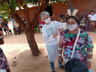 Foto de agende de saúde aplicando vacina em indígena.