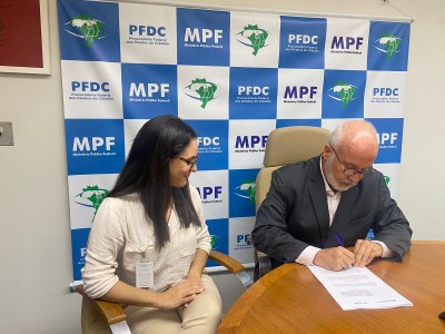 A foto mostra o procurador federal assinando o memorando de entendimento, ao lado da diretora de Projetos do Programa América Latina do AIPG, Bruna Soares. 