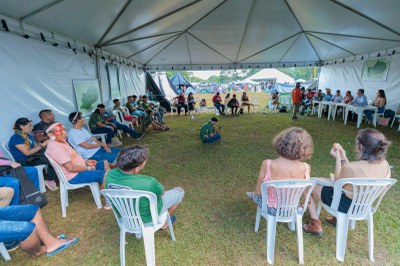 Foto de uma grande tenda, no Acampamento Terra Livre, onde indígenas estão em círculo, reunidos com procurador do MPF
