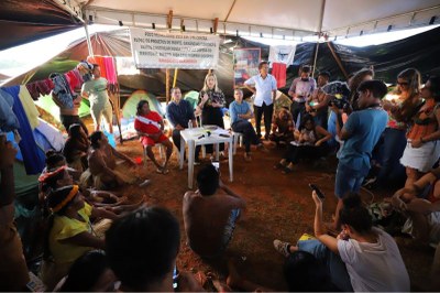 Integrantes do MPF reunidos com indígenas sob tenda branca, em chão de terra batida.
