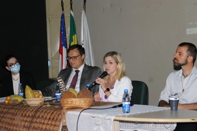 Foto da mesa de abertura do evento com quatro pessoas sentadas, sendo duas mulheres e dois homens