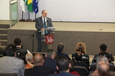 Foto mostra Augusto Aras falando ao púlpito, de frente, e o público de costas na foto