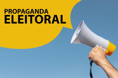 Imagem de fundo azul com uma mão segurando um megafone e um balão de diálogo amarelo saindo de dentro dele com os dizeres em cor preta: Propaganda Eleitoral. 