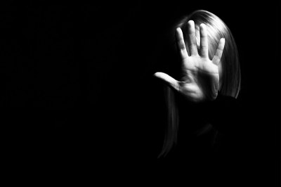 Foto em preto e branco de uma mulher com a mão direita à frente do rosto.