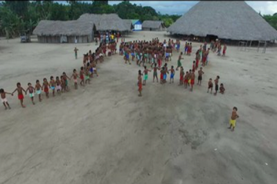 #Pracegover Foto aérea mostra indígenas reunidos em um campo de terra 