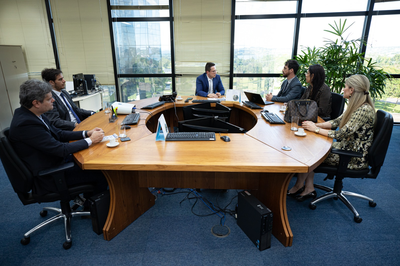 Foto de seis participantes em mesa de reunião.