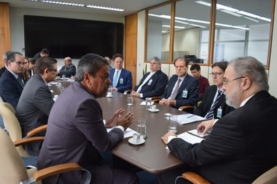 Foto da reunião, com os participantes sentados em volta de uma mesa.