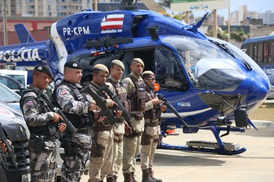 Fotografia mostra policiais militares da Bahia perfilados ao lado de helicóptero da PM