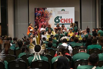 #ParaTodosVerem: foto de auditório lotado de indígenas. Ao fundo, banner da 6ª Conferência Nacional de Saúde Indígena.