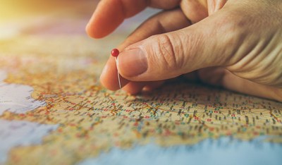 Foto de uma mão inserindo um marcador em um mapa mundi.