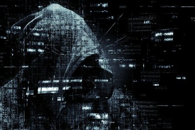Arte mostra a sombra de uma pessoa, dando a ideia de um hacker, sobre fundo preto onde aparecem códigos da internet
