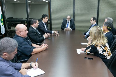 Foto mostra os participantes da reunião sentados em volta de uma mesa retangular