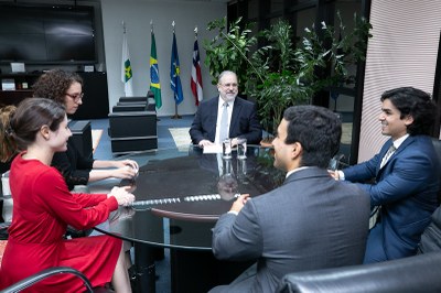 Foto mostra os participantes da reunião sentados em uma mesa redonda
