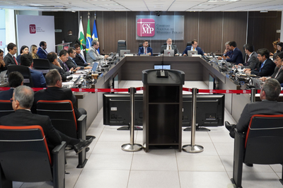 Fotografia mostra uma sessão presencial do Conselho Nacional do Ministério Público, com conselheiros reunidos em torno de uma mesa em formato "U"