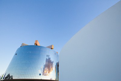 Foto de detalhes de dois prédios que abrigam a procuradoria-geral da república, em Brasília. O prédio de trás é redondo e revestido de vidro, o da direita, é branco e arredondado.