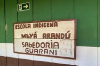 Fotografia da parede de uma escola indígena da comunidade Araçai de Piraquara com dizeres "escola indígena Mabyá Arandú, sabedoria Guarani"