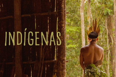 Fotografia de uma oca grande, há árvores atrás, e ao lado há um indígena de costas. Na imagem está escrito "Indígenas" na cor marrom claro.