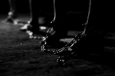Descrição da imagem #PraCegoVer: Imagem de pessoas acorrentadas pelos pés. Fonte: iStock