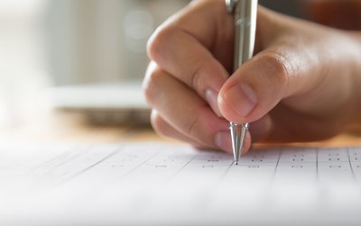 Fotografia de uma mão escrevendo em um papel com caneta