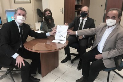 Imagem que mostra Wellington Saraiva, Germana Laureano, Dirceu Rodolfo e Ranilson Ramos, usando máscaras, segurando o documento de entrega.