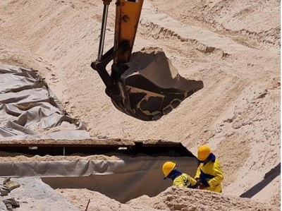 Imagem de escavadeiras na praia da Barra da Tijuca enchendo sacos de areia em obras de intervenção no bioma.