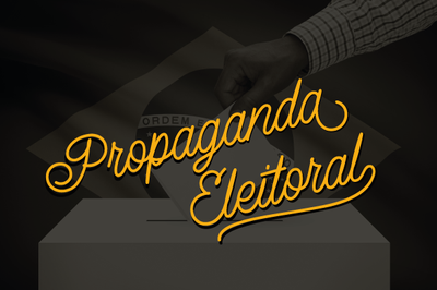 Arte retangular mostra, ao fundo, em tons de cinza, uma mão depositando um voto em uma urna tradicional e, em primeiro plano, a expressão 'Propaganda Eleitoral' em letras amarelas.
