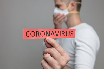 Pessoa com uma máscara segurando um papel escrito coronavírus 