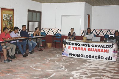 Plenária do Conselho Estadual dos Povos Indígenas exibe em sua mesa principal uma faixa onde se lê Morro dos Cavalos é terra Guarani Homologação Já!
