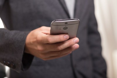 Mão de homem vestido de terno segurando um telefone celular