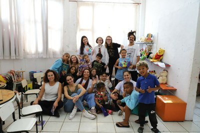 Foto do grupo de artistas e crianças que receberam a Livroteca 